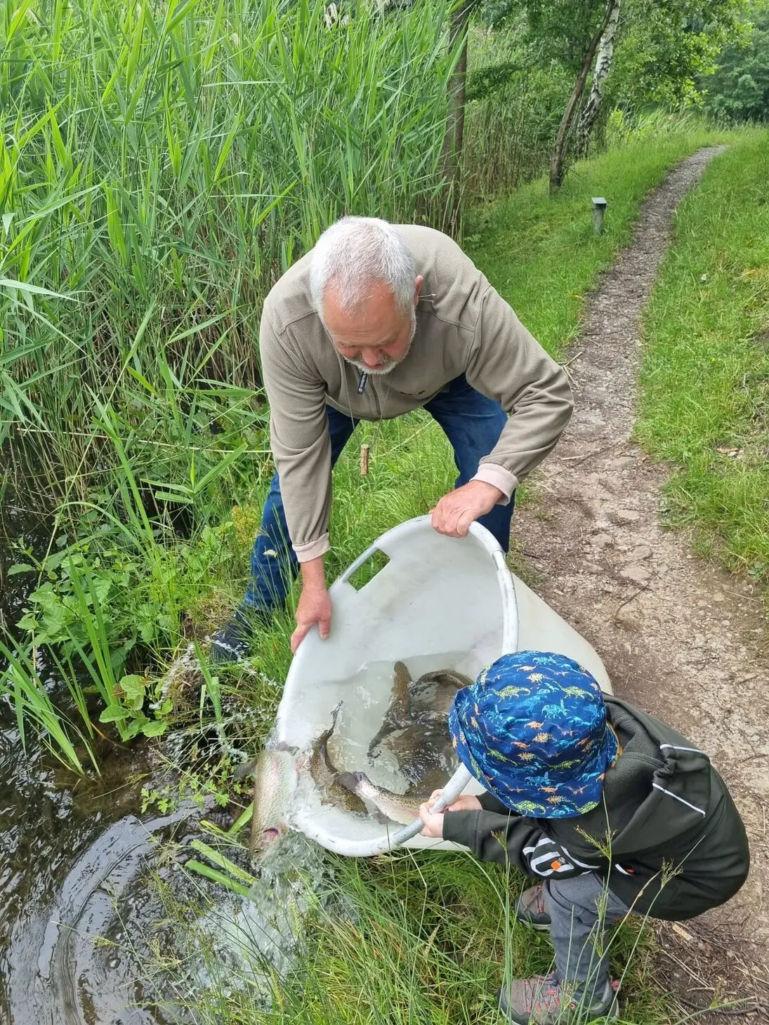 Michael Fischbesatz Mann mit Kinde beim Fischbesatz